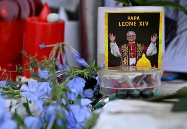 Des fleurs, des bougies et une photo du pape Léon XIV déposées au pied de la statue de Jean-Paul II, devant l’hôpital Gemelli à Rome où le pape Léon XIV est en convalescence, le 17 octobre 2026