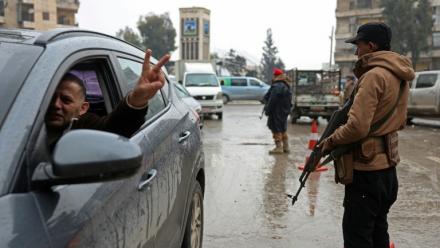 Un conducteur fait le V de la victoire en passant devant un membre des forces de syriennes, après la prise de contrôle par l'armée des quartiers kurdes d'Alep à l'issue de plusieurs jours de combats, le 11 janvier 2026
