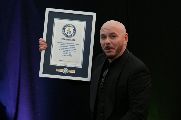 Le rappeur américain Pitbull pose avec son diplôme du Guinness des records grâce à un rassemblement de 22.141 fans portant de faux crânes chauves, le 10 juillet 2026 à Londres