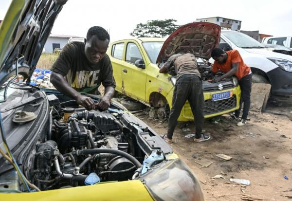 Des mécaniciens informels travaillent sur des moteurs de voiture dans le quartier d'Angré, à Abidjan, la capitale économique ivoirienne, le 21 juillet 2026.