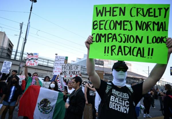 Des manifestants tiennent des pancartes et des drapeaux lors d'une manifestation contre la politique migratoire de Donald Trump, le 12 juin 2025 à Los Angeles