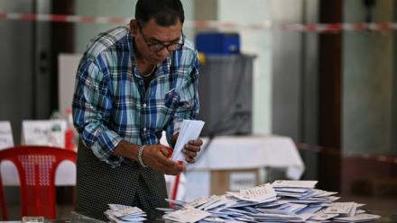 Un membre de la commission électorale birmane (UEC) trie des bulletins dans un bureau de vote de Rangoon, le 28 décembre 2025