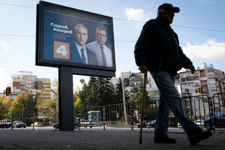 Une personne marche devant une affiche électorale du candidat à la présidentielle bulgare Andrey Gyurov et de son partenaire pour la vice-présidence Georgi Kandev, à Sofia, le 23 octobre 2026
