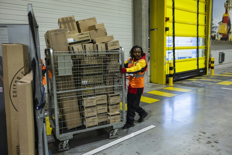 Un employé pousse un conteneur de colis dans un entrepôt DHL à Lesquin, près de Lille, le 12 novembre 2025