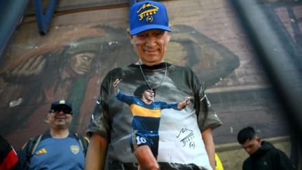 Un fan de football portant un t-shirt à l'effigie de la légende argentine Diego Maradona fait la queue devant le stade La Bombonera pour assister à la veillée funèbre de l'entraîneur argentin Miguel Angel Russo à Buenos Aires, le 9 octobre 2025. 
