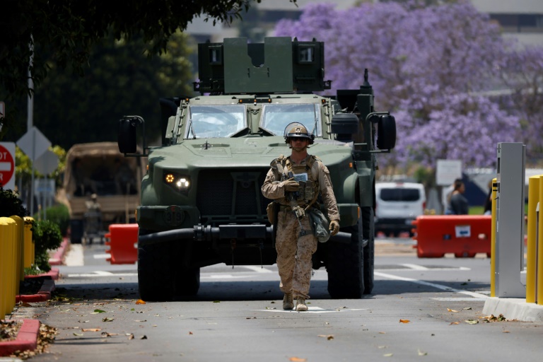 Un Marine marche devant un véhicule blindé dans le quartier de Westwood à Los Angeles le 13 juin 2025.
