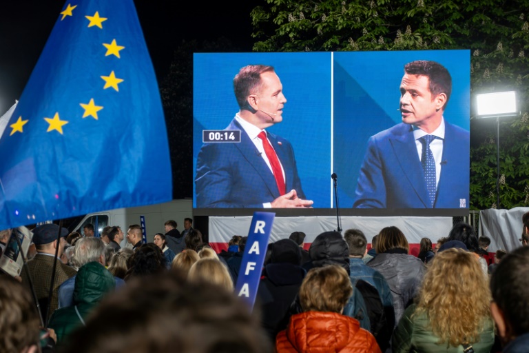 Des partisans du maire de Varsovie pro-européen, Rafal Trzaskowski (d), observent un débat entre leur candidat et son principal adversaire à la présidentielle, le nationaliste Karol Nawrocki (g), à Varsovie, le 12 mai 2025