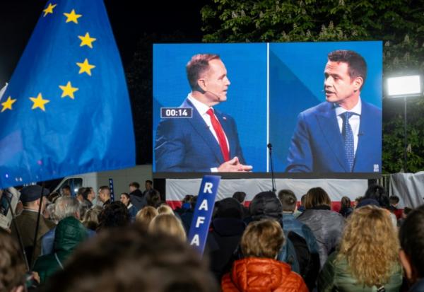 Des partisans du maire de Varsovie pro-européen, Rafal Trzaskowski (d), observent un débat entre leur candidat et son principal adversaire à la présidentielle, le nationaliste Karol Nawrocki (g), à Varsovie, le 12 mai 2025