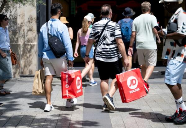 Des passants portent des sacs de courses à Paris, le 25 juin 2025, premier jour des soldes d'été en France