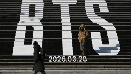 Des piétons le long d'escaliers décorés du logo du groupe de K-pop BTS, près de la place Gwanghwamun à Séoul, le 14 janvier 2026