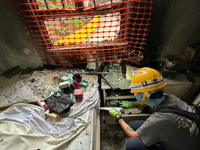 Sur cette photo prise et transmise le 23 avril 2026 par Bowie Chan, un habitant de Wang Fuk Court, son épouse Annie Tse fouille les tiroirs d'un meuble de leur appartement endommagé par l'incendie de novembre, à Hong Kong