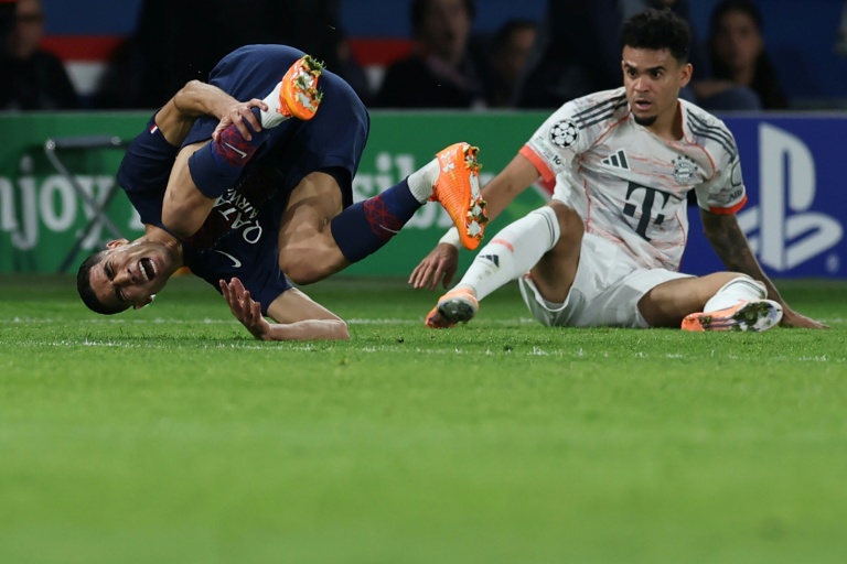 Le défenseur du Paris SG Achraf Hakimi (G) blessé lors de la défaite contre le Bayern Munich (2-1) à la suite d'un tacle de l'attaquant Luis Diaz (D), le 4 novembre 2025 au Parc des Princes