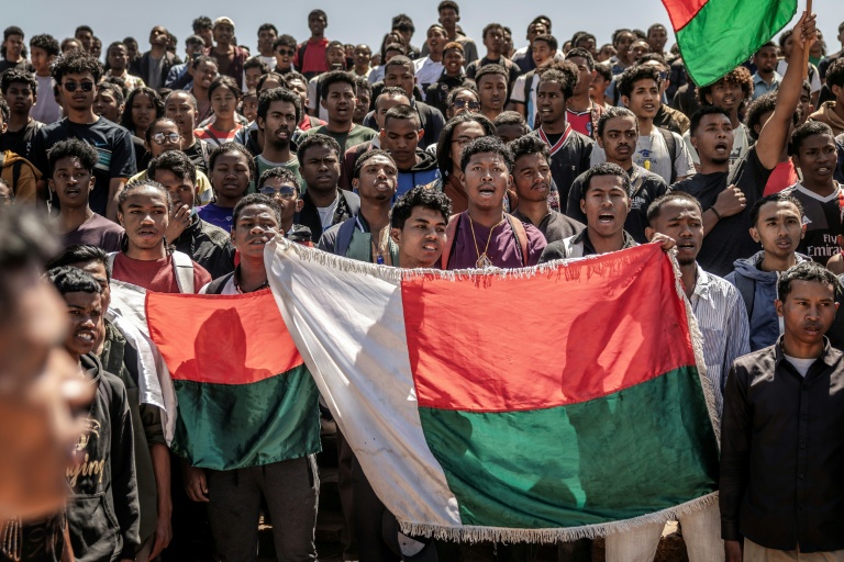 Des étudiants chantent l'hymne national en tenant des drapeaux malgaches avant de se rendre à un rassemblement de la société civile, à l'université Ankatso d'Antananarivo, le 13 octobre 2025