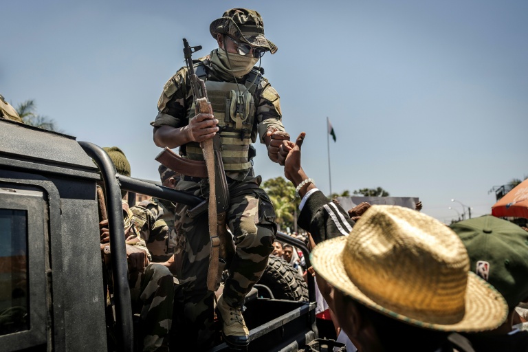 Un militaire malgache salue du poing un civil alors que des manifestants se rassemblent pour un meeting de la société civile devant l'hôtel de ville d'Antananarivo, le 13 octobre 2025