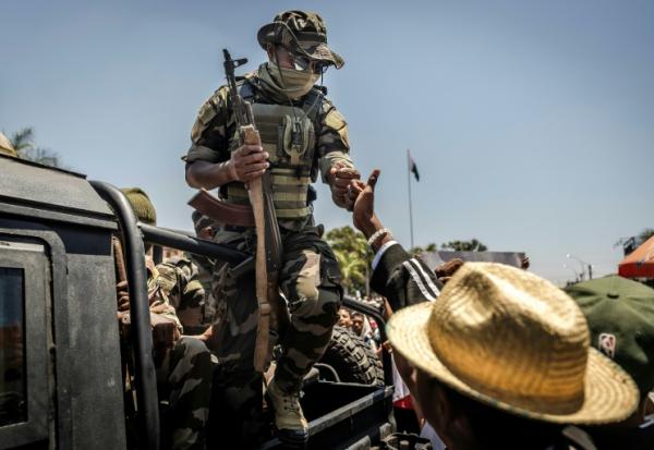 Un militaire malgache salue du poing un civil alors que des manifestants se rassemblent pour un meeting de la société civile devant l'hôtel de ville d'Antananarivo, le 13 octobre 2025