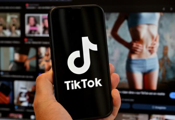 Le logo de Tik Tok sur un smartphone devant un écran affichant l'image d'une femme très mince, alors que la tendance "skinnytok" promouvant la minceur inquiète les experts, le 7 mai 2025