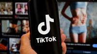 Le logo de Tik Tok sur un smartphone devant un écran affichant l'image d'une femme très mince, alors que la tendance "skinnytok" promouvant la minceur inquiète les experts, le 7 mai 2025