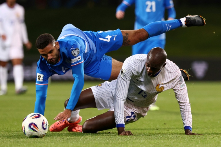 L'Islandais Victor Palsson (en bleu) et le Français Jean-Philippe Mateta sont à la luute en match de qualifications pour le Mondial-2026, le 13 octobre 2025 à Reykjavik