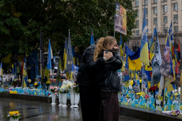Des passants devant un mémorial improvisé pour les soldats ukrainiens et étrangers morts au combat, à Kiev le 7 octobre 2025