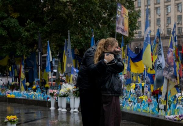 Des passants devant un mémorial improvisé pour les soldats ukrainiens et étrangers morts au combat, à Kiev le 7 octobre 2025