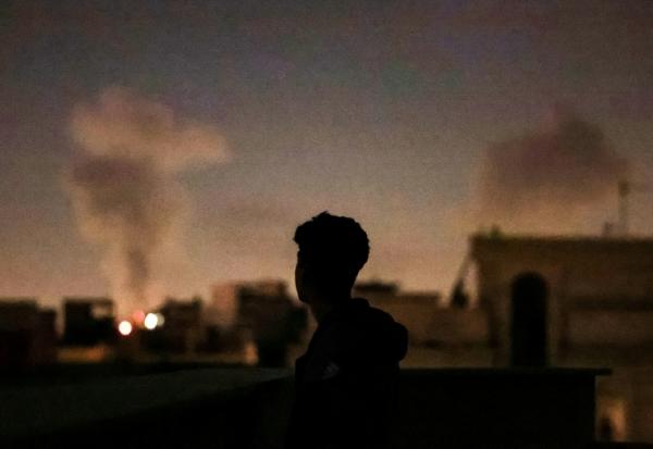 Une personne regarde la fumée de frappes aériennes sur Téhéran, le 4 mars 2026 en Iran