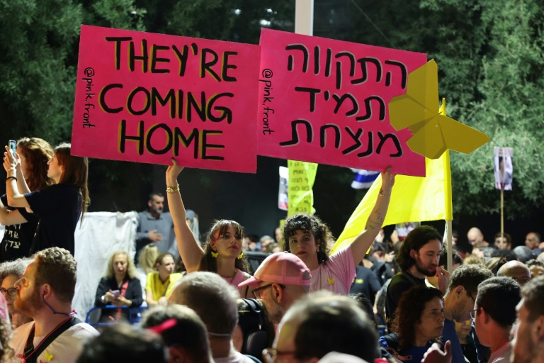 Des femmes brandissent des pancartes lors d’un rassemblement sur la place des Otages à Tel-Aviv, en Israël, avant la libération prévue de dizaines d'otages retenus dans la bande de Gaza, le 11 octobre 2025