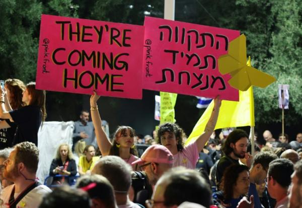 Des femmes brandissent des pancartes lors d’un rassemblement sur la place des Otages à Tel-Aviv, en Israël, avant la libération prévue de dizaines d'otages retenus dans la bande de Gaza, le 11 octobre 2025