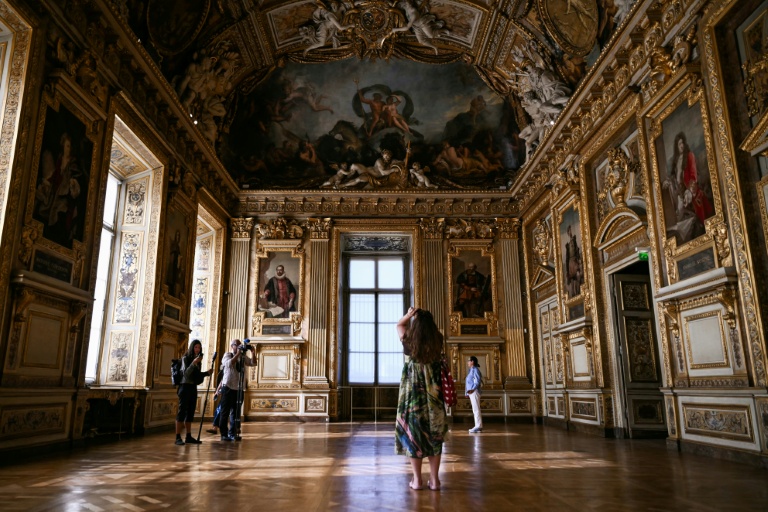 Des visiteurs prennent en photo la fenêtre par laquelle des cambrioleurs se sont introduits en octobre 2025 dans la galerie d'Apollon du musée du Louvre, lors de la réouverture des lieux, le 22 juillet 2026 à Paris