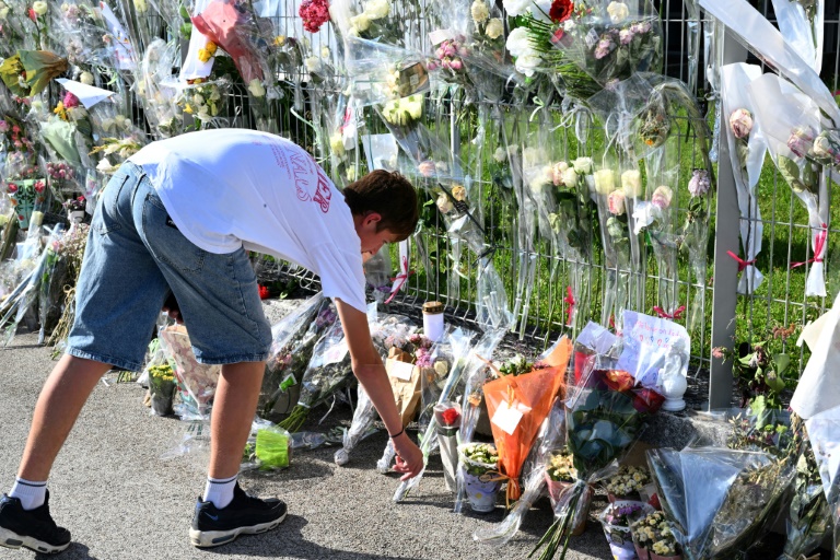 Un jeune homme dépose des fleurs devant les grilles du collège Françoise-Dolto, en hommage à Mélanie, la surveillante tuée par un élève, avant une marche silencieuse à Nogent, le 13 juin 2025 en Haute-Marne