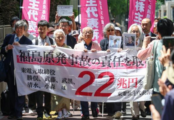 Des plaignants déploient une banderole demandant aux anciens responsables de la compagnie Tepco, opérant la centrale nucléaire de Fukushima, de "prendre la responsabilité de l'accident nucléaire de Fukushima - 22 000 milliards de yens", à Tokyo le 6 juin 2025