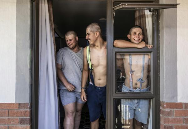 Des étudiants, Belly Sharpe (C), 18, et Eben Mans (D), 20, rient avec un ami à l'entrée de leur dortoir Vaalbos dans l'enclave afrikaner d'Orania en Afrique du Sud, le 28 janvier 2026.