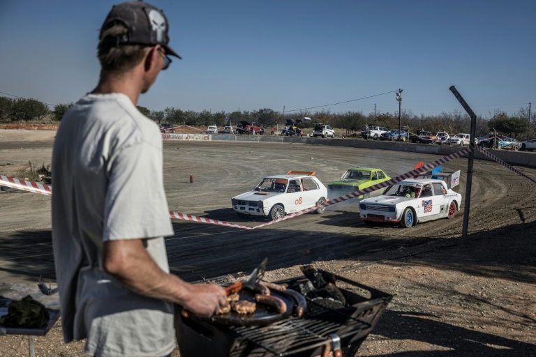 Un spectateur grille de la viande sur un braai (barbecue) devant une course de voiture sur l'ovale de terre de l'enclave afrikane en Afrique du Sud, le 30 mai 2026.