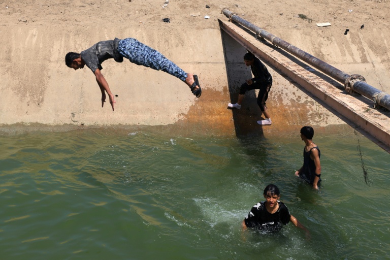 Des jeunes tentent de se rafraîchir en plongeant dans l'eau, à Diwaniyah, dans le sud de l'Irak, le 10 août 2025