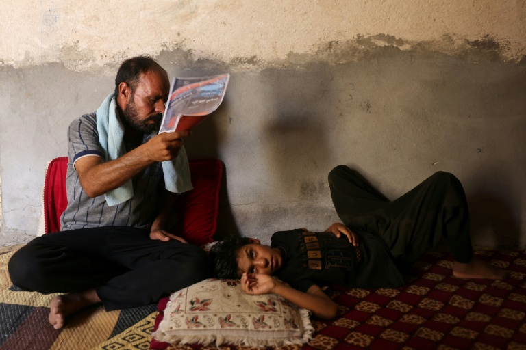 Un homme tente de rafraîchir son fils, à Hilla, dans le centre de l'Irak, le 10 août 2025
