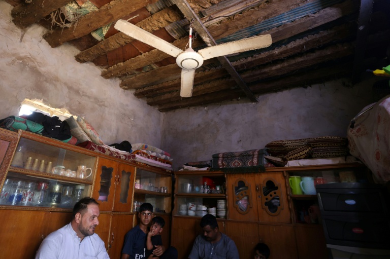 Une famille irakienne sous un ventilateur, à Hilla, dans le centre de l'Irak, le 10 août 2025