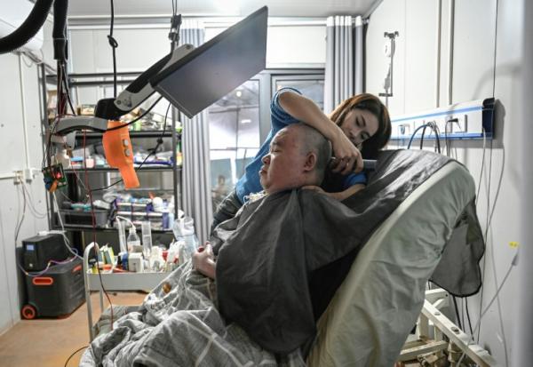 Li Xia, tétraplégique, est aidé par sa soeur Li Qian, chez eux, à Chongqing, en Chine, le 16 décembre 2025