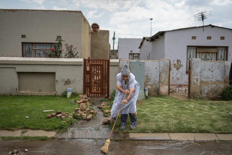 Morongoe Lephato tente d'évacuer des eaux usées devant sa maison du township de Katlehong, près de Johannesburg, le 5 octobre 2026.