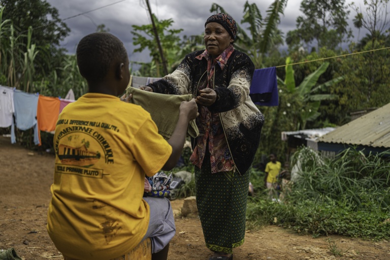 Marie-Thérèse Tsesi, une nourrice de 63 ans, plie du linge avec l'un des cinq enfants orphelins d'Ebola dont elle s'occupe à son domicile à Mongbwalu, dans le nord-est de la RDC, le 11 octobre 2026
