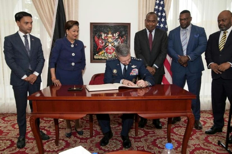 Photo diffusée par le service de presse de la présidence de Trinité-et-Tobago montrant le chef d'état-major américain, le général Dan Caine, signant un document avec la Première ministre de Trinité-et-Tobago, Kamla Persad-Bissessar (2e à gauche), lors de sa visite à Port d'Espagne, le 25 novembre 2025