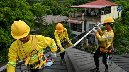 Des ouvriers installent des panneaux solaires sur un toit à Carmona, aux Philippines, le 9 juillet 2026