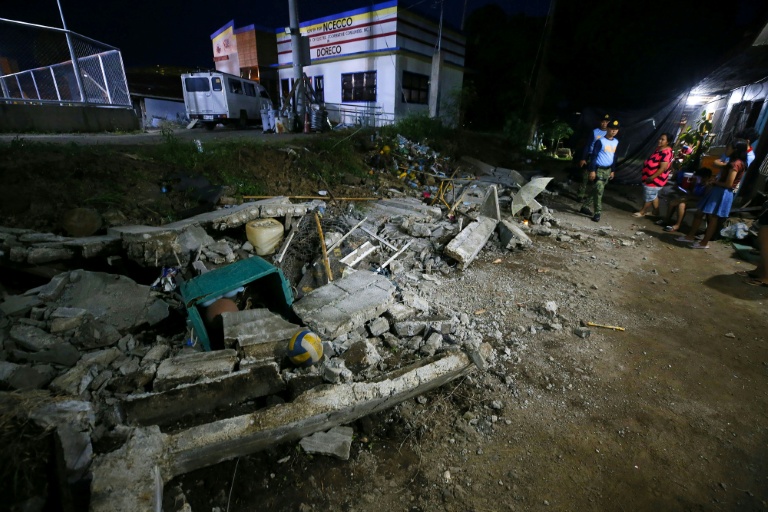 Des policiers près des décombres d'un mur effondré à Mati, sur l'île méridionale de Mindanao, le 10 octobre 2025, après un tremblement de terre qui a frappé les Philippines