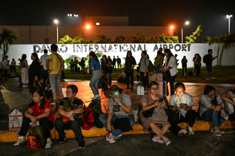 Des voyageurs attendent de recevoir l'autorisation du personnel de l'aéroport pour entrer dans l'aéroport de Davao, le 10 octobre 2025, après une réplique d'un tremblement de terre précédent aux Philippines