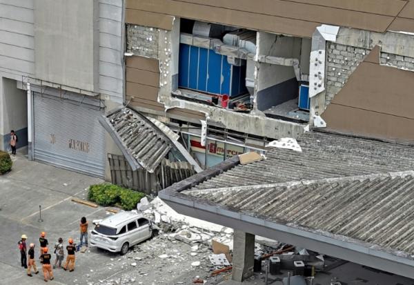 Les autorités inspectent un mur endommagé à l'extérieur d'un centre commercial à Butuan, sur l'île méridionale de Mindanao, le 10 octobre 2025, après un séisme qui a frappé le sud des Philippines