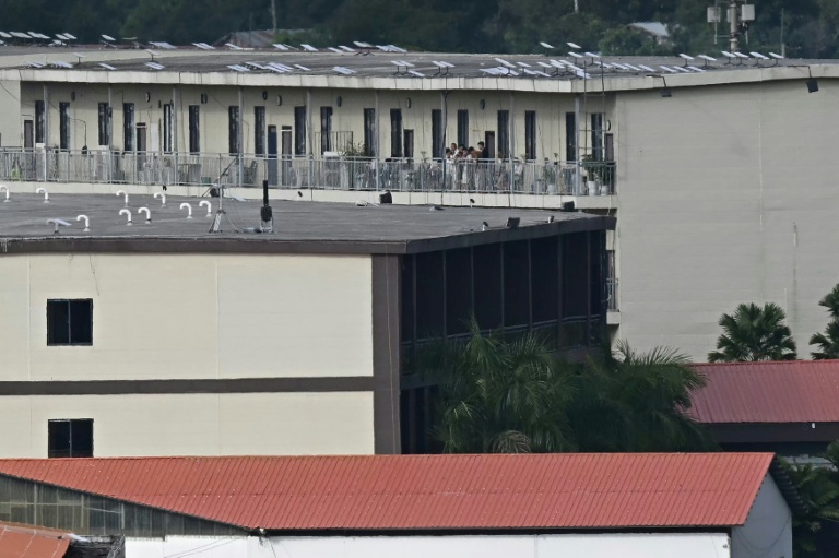 Des personnes sur le balcon d'un bâtiment avec ce qui semble être des antennes paraboliques Starlink sur le toit du complexe KK Park dans le canton de Myawaddy, en Birmanie, vu depuis le district de Mae Sot, dans la province frontalière de Tak, le 17 septembre 2025 en Thaïlande