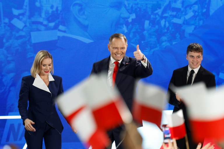 Karol Nawrocki, accompagné de son épouse Marta, salue ses partisans après l'annonce des sondages de sortie des urnes, lors du deuxième tour de la présidentielle, le 1er juin 2025 à Varsovie, en Pologne
