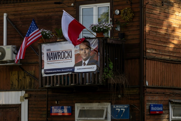 Une affiche électorale de Karol Nawrocki, candidat à l'élection présidentielle, soutenu par le parti de droite polonais Droit et Justice (PiS), exposée sur un balcon à côté des drapeaux polonais et américain, le 6 mai 2025 à Varsovie