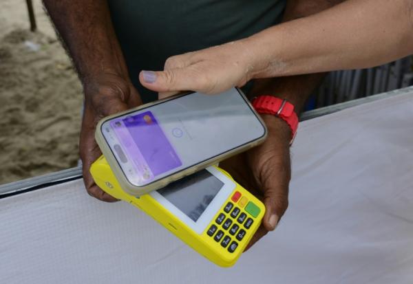 Une femme règle un achat sur la plage de Copacabana à l'aide du système de paiement instantané brésilien PIX, à Rio de Janeiro, le 9 juillet 2026 au Brésil