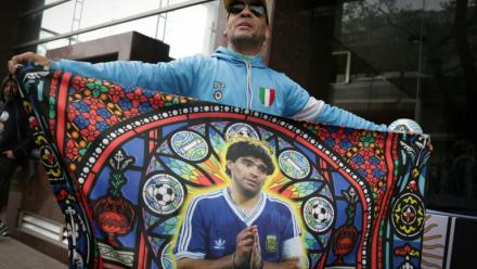 Un supporter tient un drapeau à l'effigie de Diego Maradona, avant une audience du procès sur le décès de la légende du football argentin, devant le tribunal à San Isidro, le 8 octobre 2026 en Argentine