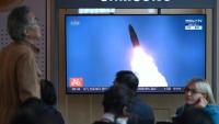 Des personnes sont assises devant un écran de télévision diffusant un journal télévisé avec des images d'archives d'un test de missile nord-coréen, dans une gare de Séoul, le 22 octobre 2025
