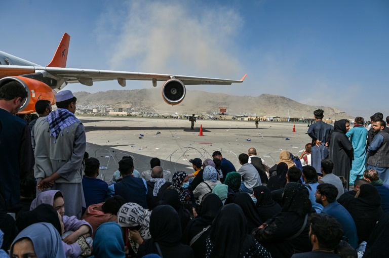 Des Afghans assis sur le tarmac de l'aéroport de Kaboul pris d'assaut dans l'espoir d'une évacuation après la reprise de la capitale par les talibans, le 16 août 2021 